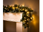Weihnachtsgirlande mit warmweißen LED-Lichtern auf einem weißen Kaminsims.