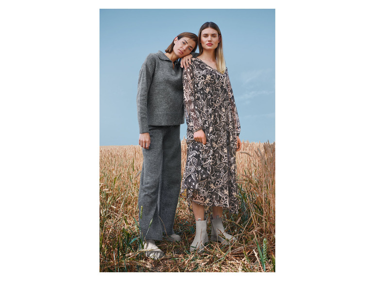 Zwei Frauen auf einem Feld mit einem grauen Pullover und einem gemusterten Kleid.