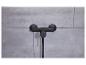 Eine schwarze Duschgarnitur mit Thermostat und Handbrause, montiert an einer grauen Fliesenwand.