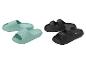 Grüne Pantoletten und schwarze Sandalen auf weißem Hintergrund.