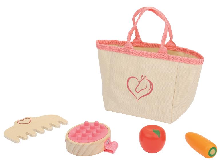 Eine rosa Tasche mit einem Pferdelogo, eine Holzbürste, ein Kamm und Spielzeuggemüse.
