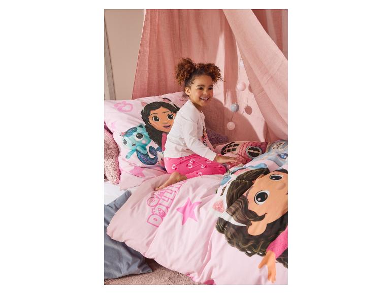 Rosa Gabby's Dollhouse Bettwäsche und ein lächelndes Mädchen.