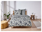 Ein Bett mit grauer Bettwäsche mit Blumenmuster.