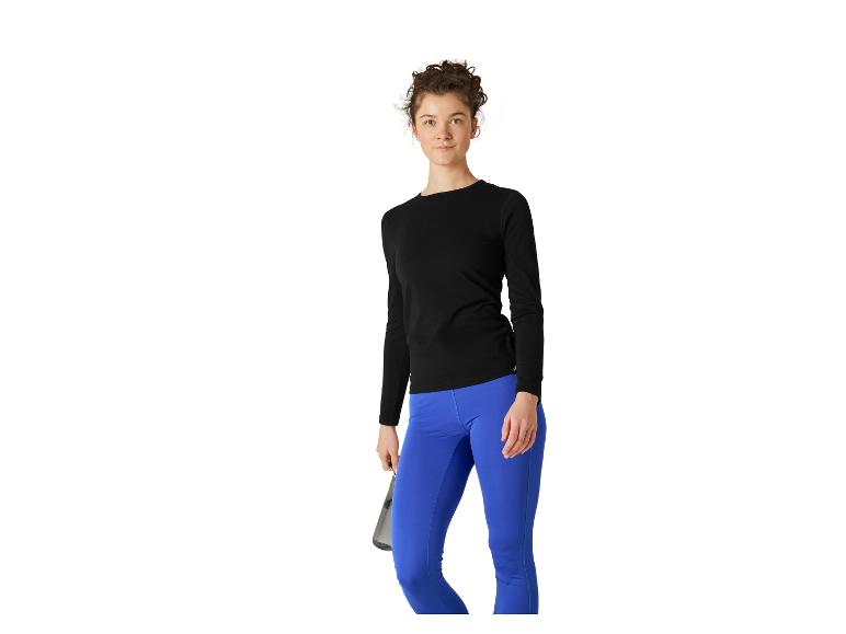 Frau in schwarzem Langarmshirt und blauen Leggings, hält eine Wasserflasche.