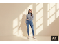 Frau in grauem Rollkragenpullover und Jeans steht vor einer Wand mit Schatten.