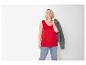 Frau in rotem ärmellosem Top und Jeans, mit grauer Jacke über der Schulter.