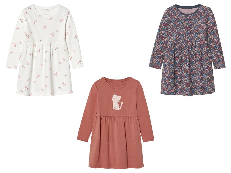 Drei langärmelige Mädchenkleider mit Blumen- und Katzenmotiven.