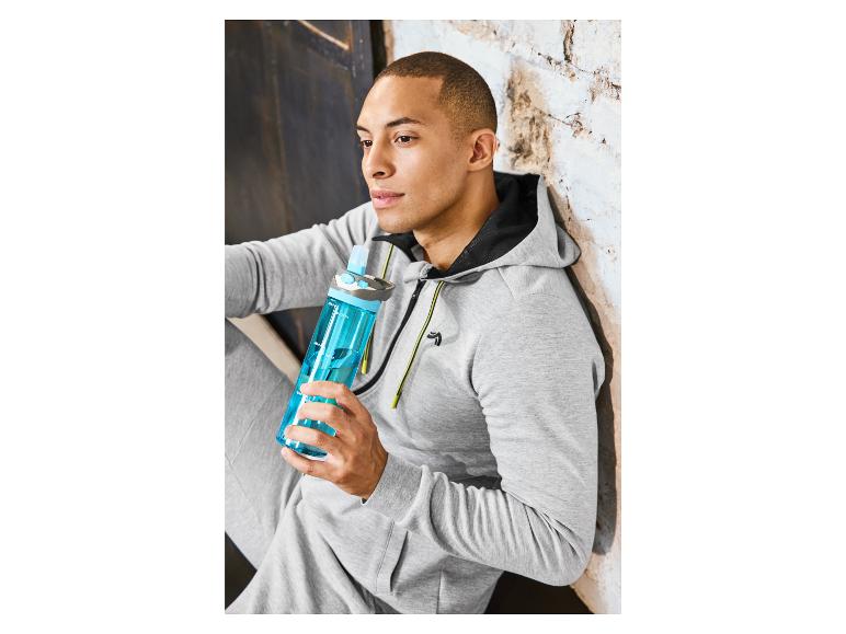 Mann in grauem Hoodie trinkt aus einer blauen Wasserflasche.