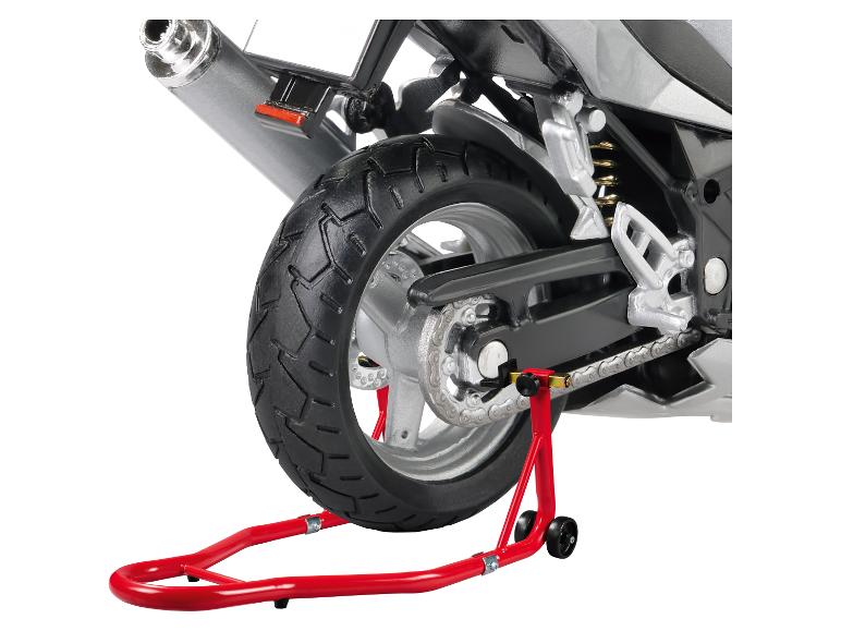 Hinterrad eines Motorrads auf einem roten Ständer, zeigt Reifen, Kette und Auspuff