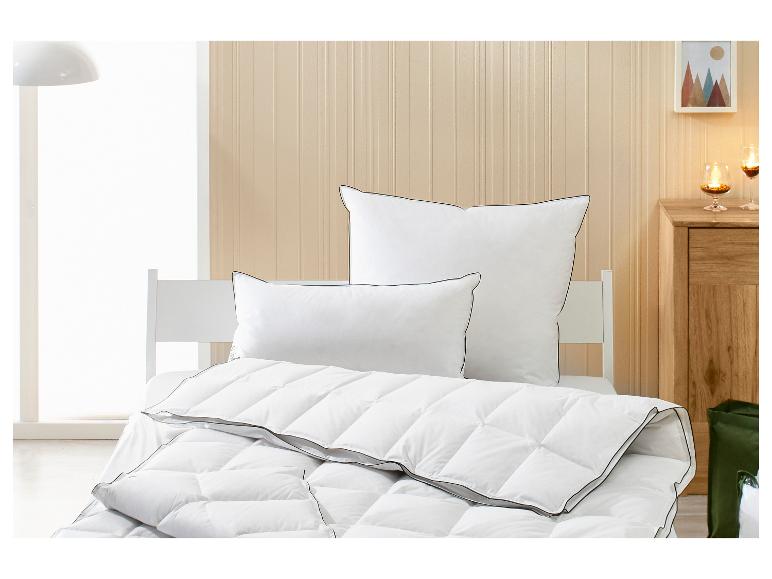 Weiße Bettdecke und Kissen mit schwarzem Rand auf einem Bett in einem hellen Schlafzimmer.