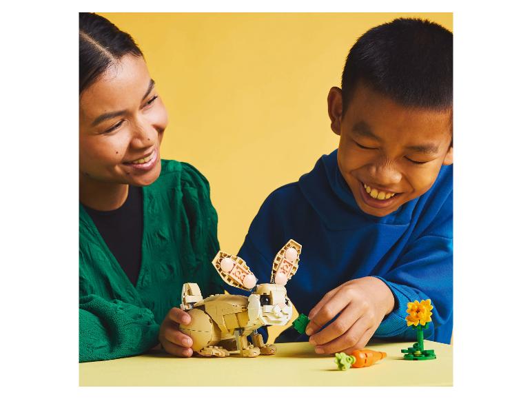 Eine Frau und ein Kind spielen mit einem LEGO-Hasen und Karotten.