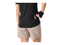 Frau in schwarzem Sporttop und beigen Shorts, steckt einen Snackriegel in eine Gesäßtasche.