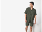 Mann in dunkelgrünem Kurzarmhemd und passenden Shorts, lächelnd und nach rechts blickend.