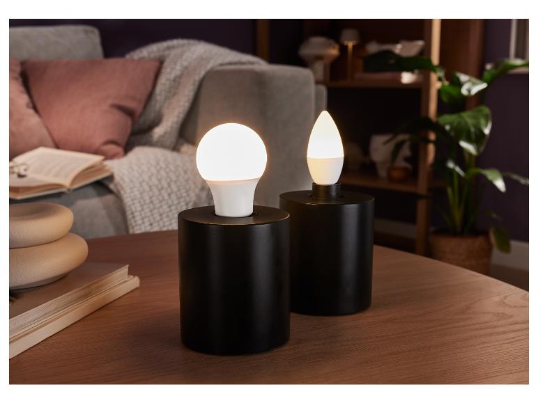Zwei schwarze Lampen mit runden und tropfenförmigen LED-Lampen auf einem Holztisch.