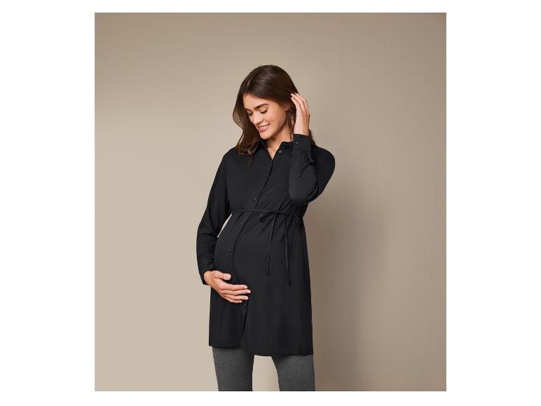 Schwangerer Frau in einem schwarzen Hemd und grauen Hosen.