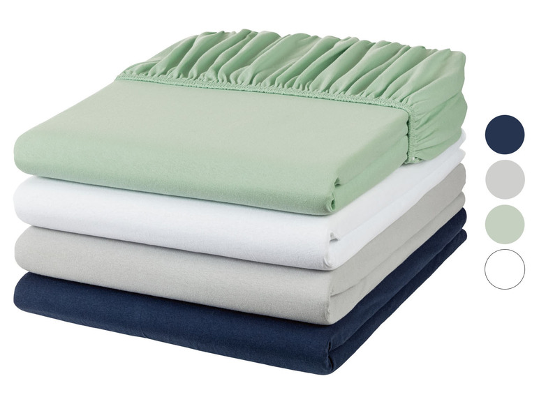 Ein Stapel Bettwäsche in verschiedenen Farben, darunter grün, weiß und dunkelblau.