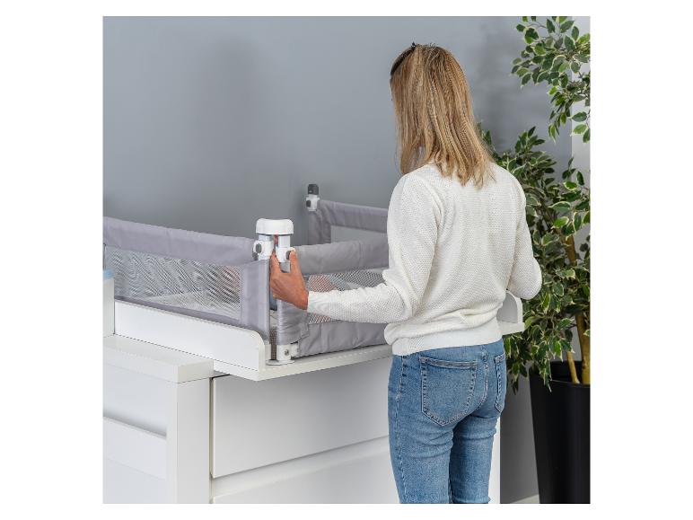 Eine Frau montiert ein Baby-Sicherheitsgitter an einem Möbelstück.