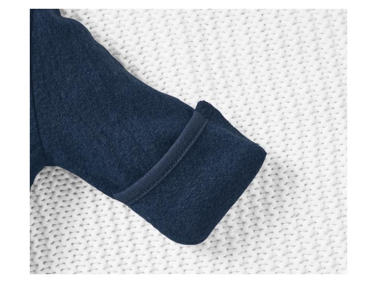 Dunkelblauer Fleece-Overall auf weißem Strickstoff.