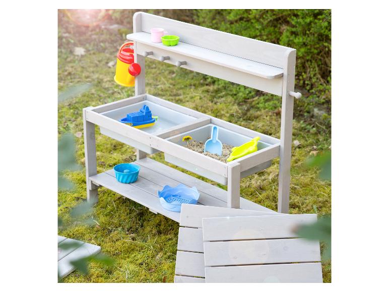 Holz-Sand- und Wassertisch mit farbenfrohem Zubehör in einem Garten.