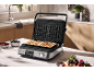 Modernes Waffeleisen mit zwei frisch gebackenen Waffeln auf einer Küchenarbeitsplatte.