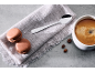 Kaffee mit Macarons, Löffel und Kaffeebohnen auf einem Leinentuch.
