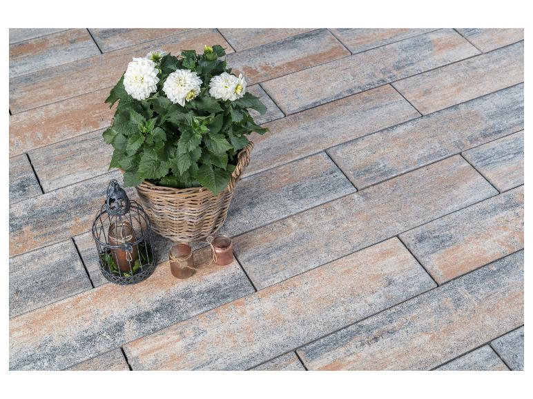 Weiße Dahlien im Weidenkorb und Laternen auf Terrassenplatten in Holzoptik.