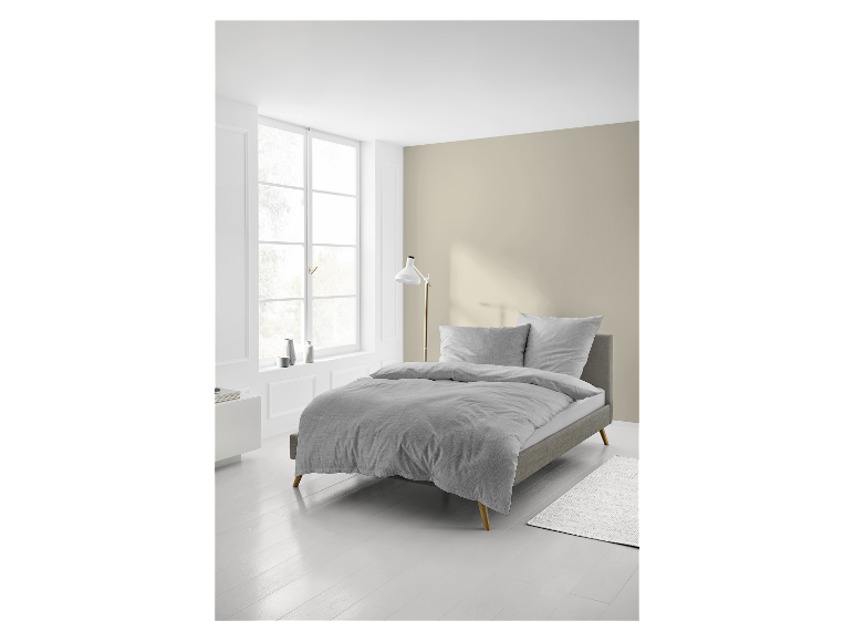 Hellgraues Bettwäsche-Set und modernes Bett in einem Schlafzimmer.