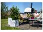 Pflanztöpfe mit Pflanzen auf einer Holzterrasse, mit einer entspannenden Frau im Hintergrund.