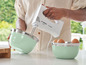 Eine Person verwendet einen Bosch CleverMixx Handmixer mit zwei Schüsseln.