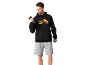 Mann in schwarzem Hoodie mit orangefarbenem Logo und grauen Shorts, hält Hanteln.