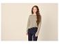 Frau in khakifarbenem Langarmpullover und dunklen Jeans.