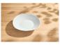 Leere weiße Schale auf einem hellen Holztisch mit Blattschatten.
