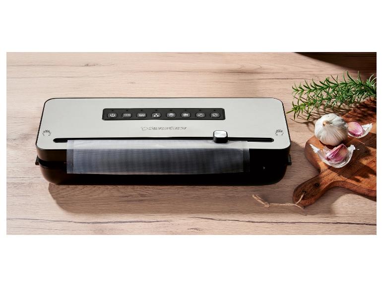 SilverCrest Vakuumiergerät auf einem Holztisch mit Knoblauch und Rosmarin.