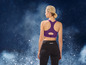 Eine Frau trägt einen lila Sport-BH und schwarze Leggings.