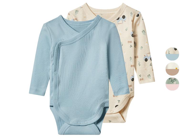 Zwei Babybodys, einer blau und einer beige mit Bauernhofmotiv, mit Druckknöpfen.