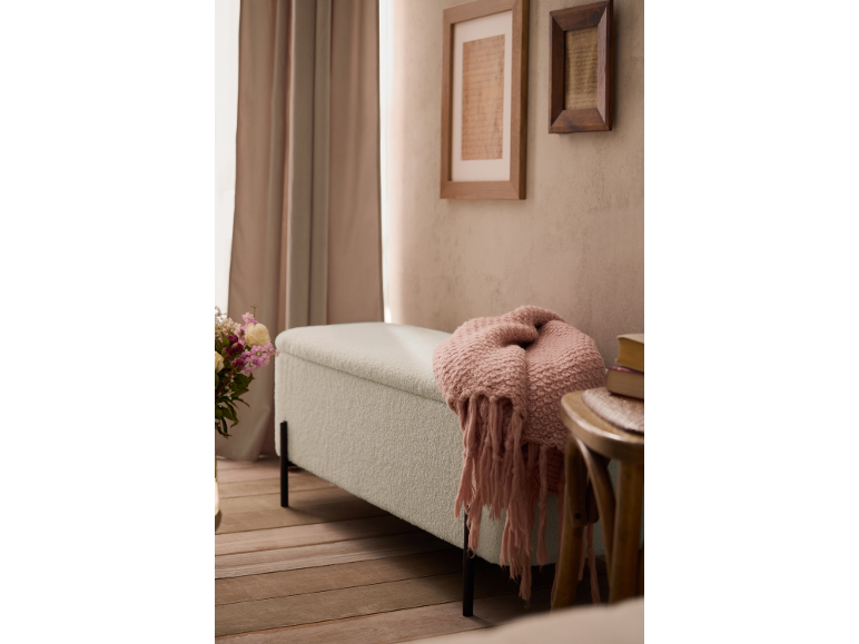 Hellgrüne Bank mit rosa Decke in einem Schlafzimmer mit Holzboden und gerahmten Bildern.