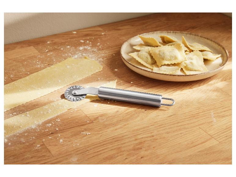 Ravioli und Nudelteig auf einem Holztisch mit einem Nudelschneider.