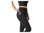 Frau in schwarzen Leggings und Crop Top, die ein Telefon in die Seitentasche steckt.