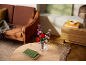 Eine Vase mit roten und rosa Spielzeugblumen auf einem Holztisch in einem gemütlichen Wohnzimmer.
