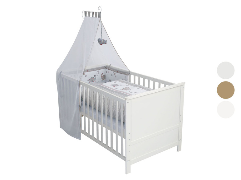 Weißes Babybett mit Himmel und Bettwäsche mit Elefantenmotiv.
