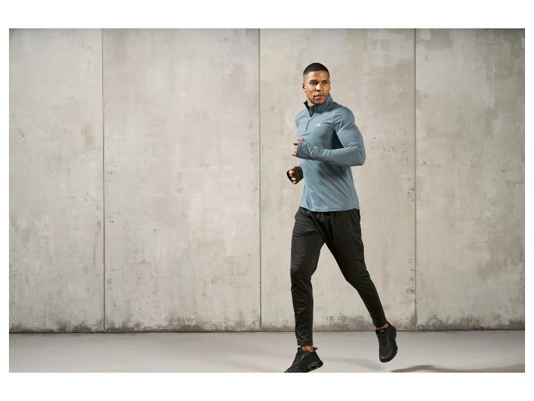 Mann in einem grauen Shirt und schwarzen Hosen mit Sneakers, der rennt.