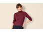 Frau in bordeauxrotem Rippen-Rollkragenpullover und dunkelblauer Hose