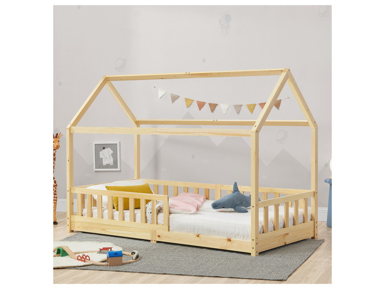 Ein Hausbett aus Holz mit Gitter und ausziehbarer Schublade.