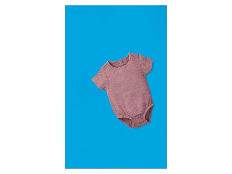 Rosa kurzärmeliger Baby-Body auf blauem Hintergrund.