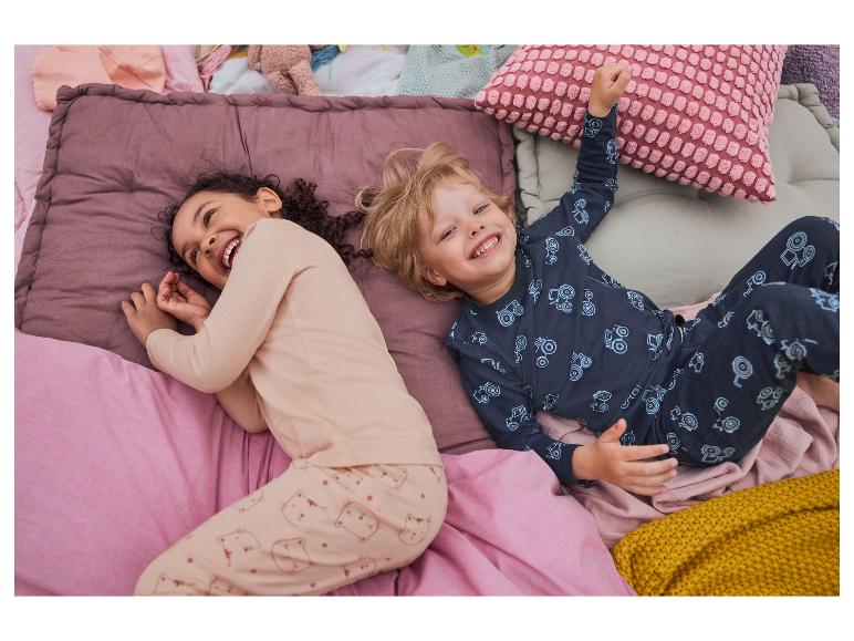 Kinder lachen im Bett in ihren Pyjamas.