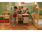 Kind spielt mit einer Spielzeug-Werkbank in einem weihnachtlich dekorierten Zimmer.