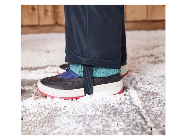 Schwarze Schneestiefel mit rosa Rand auf Schnee