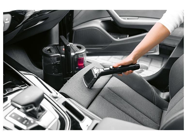 Hand-Textilreiniger reinigt einen Autositz.