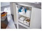 Ein offener Küchenschrank mit einem Philips Dampfbügeleisen, Handtüchern und Wäscheklammern.