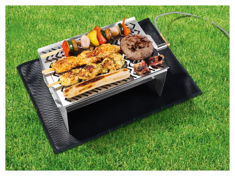 Gasgrill mit Spießen, Burger und Wurst auf Gras.